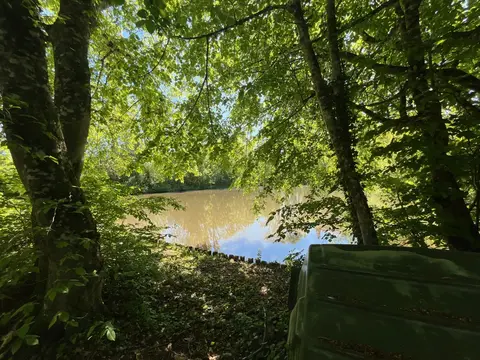 Vue ombragée sur l’étang depuis le parc du gîte de groupe